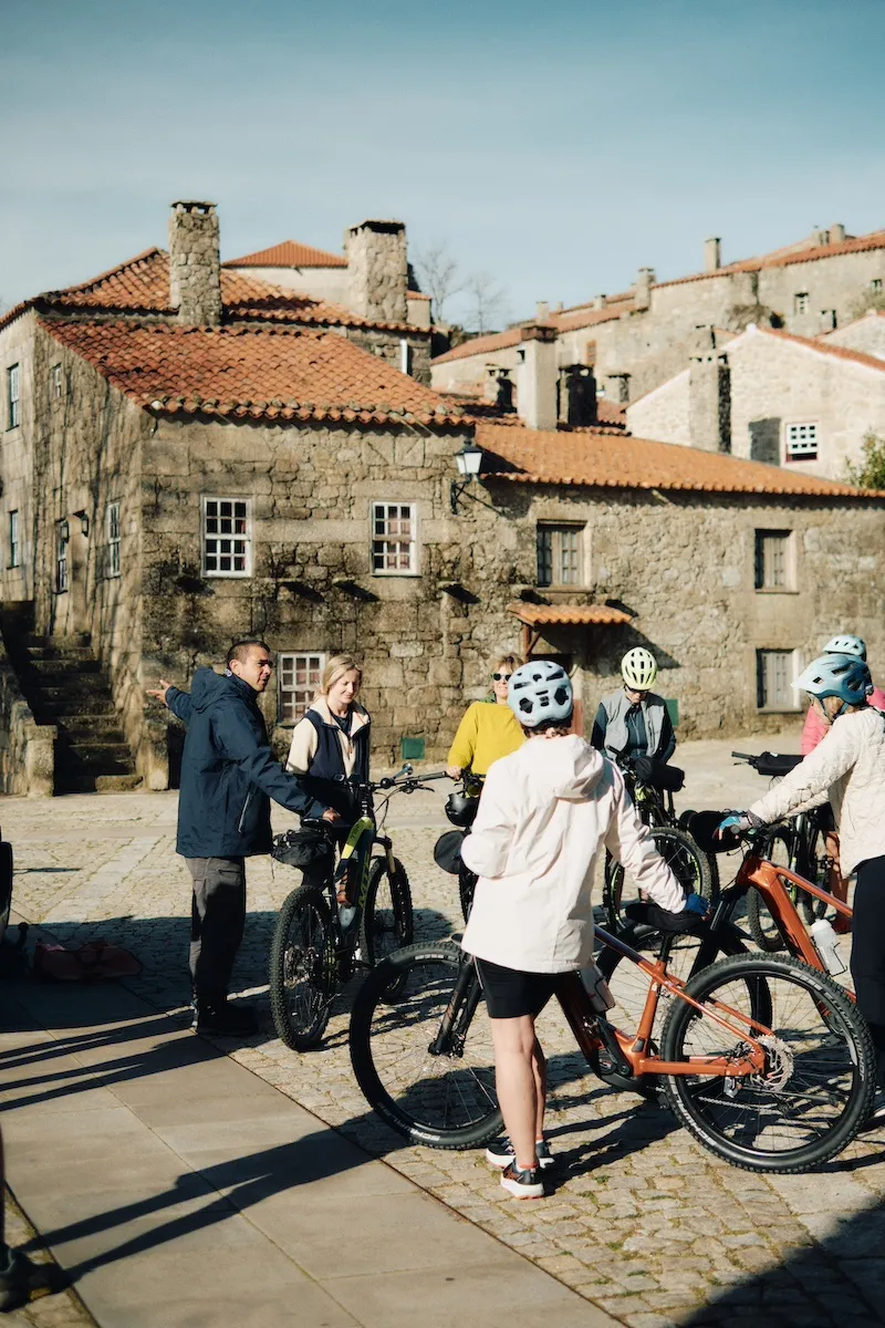 Guests and their bikes in a square of the historic villages of coa valley, portugal