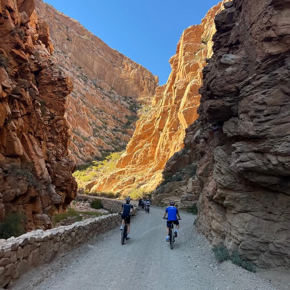 Cyclists riding through gorge beneath blue sky, Karoo, South Africa