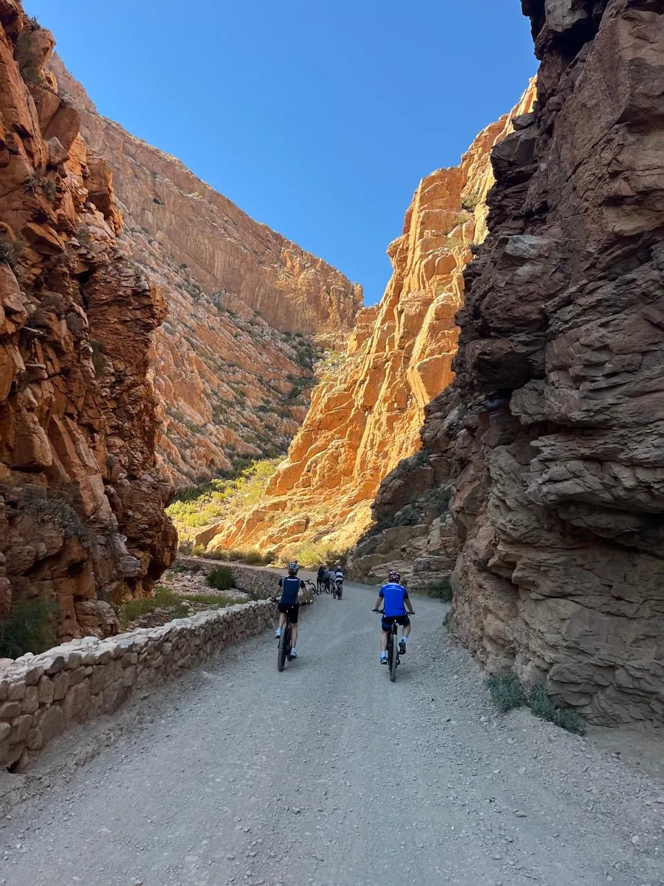 Cyclists riding through gorge beneath blue sky, Karoo, South Africa