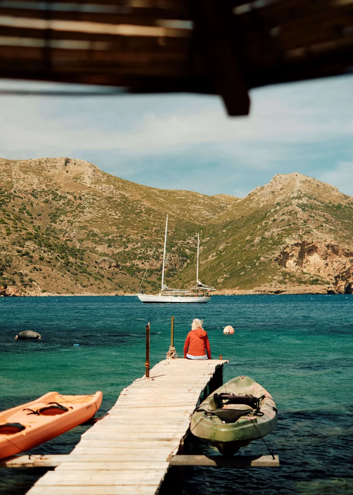 A solo traveller on the pier, overlooking the sea and boats, in the Mani, Greece's Peloponnese