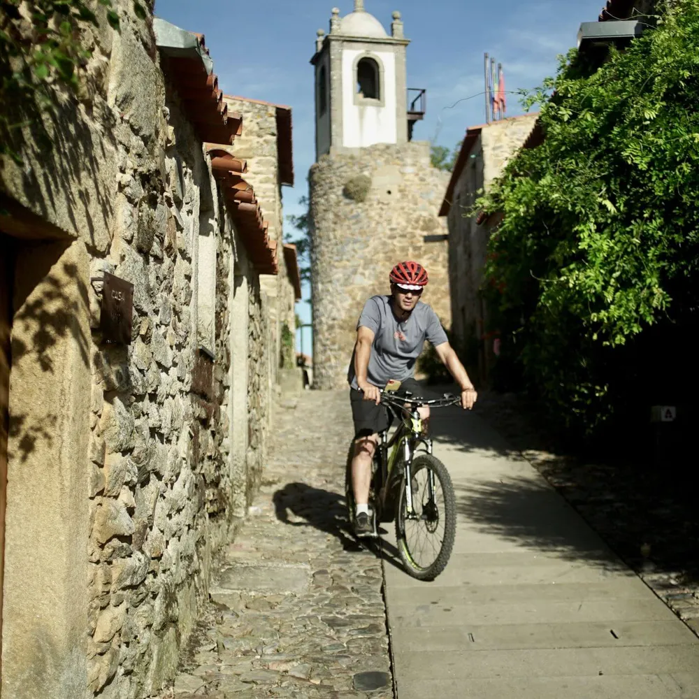 A Slow Cyclist guide riding through a stone village in Portugal's Douro region.