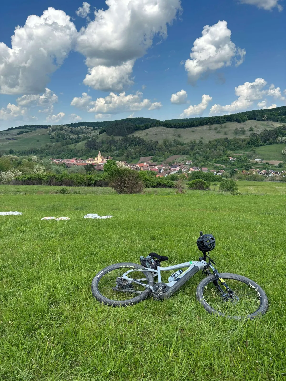 A bike in a meadow overlooking a town in Transylvania on a Slow Cyclist journey