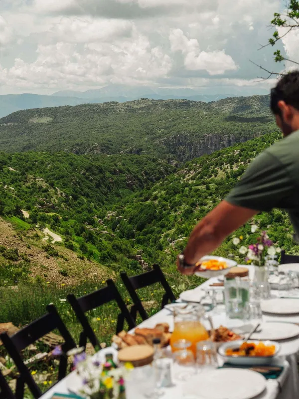 A picnic table with a view over the mountains of Zagori, Greece, set for Slow Cyclists to enjoy a Greek lunch.