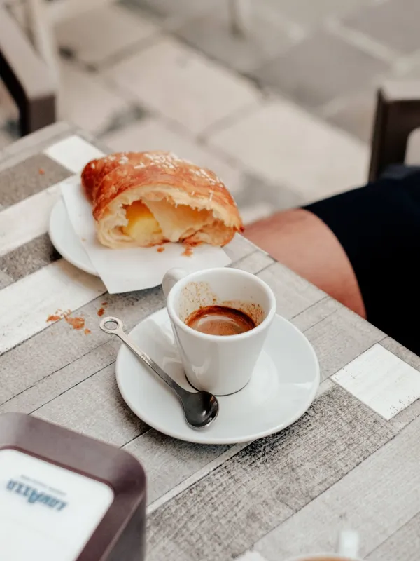 An outdoor cafe table in the village of Caramanico with a pastry and espresso