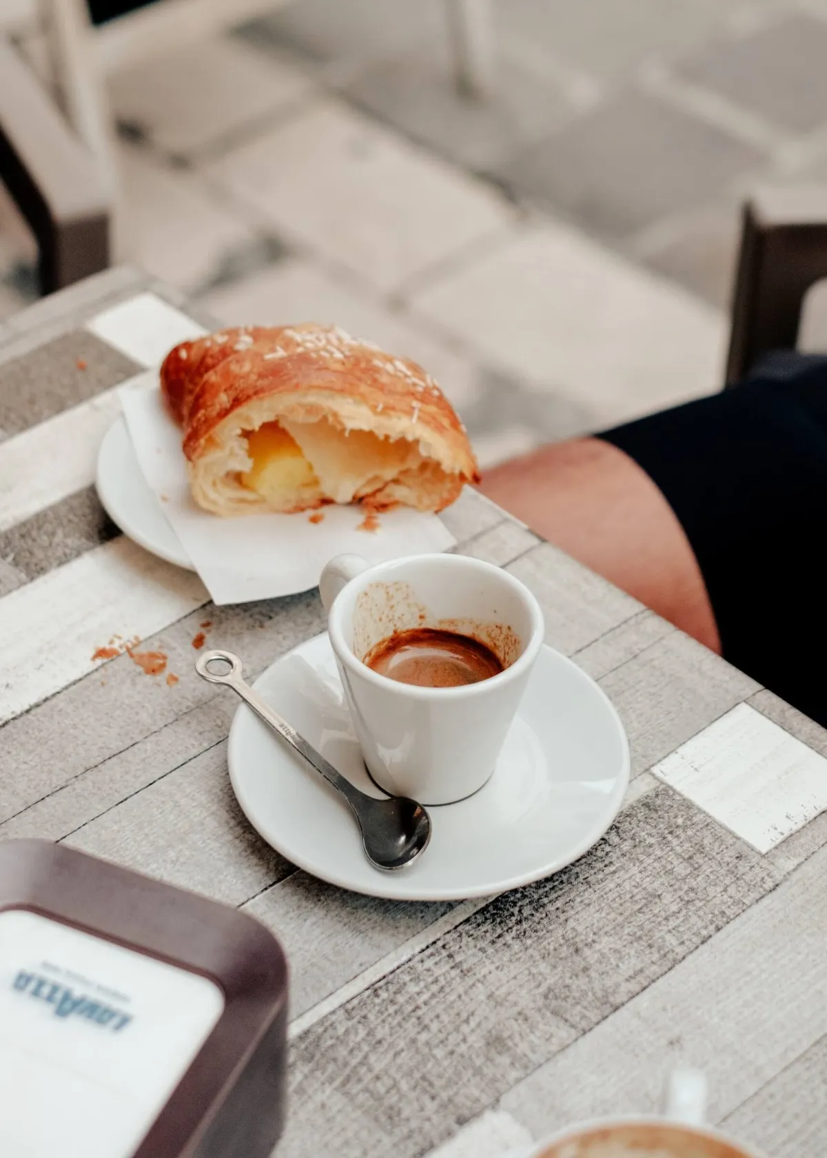 An outdoor cafe table in the village of Caramanico with a pastry and espresso