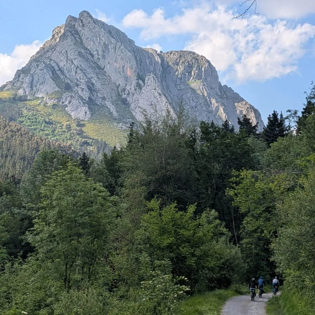 A group of Slow Cyclists riding past a mountain in Spanish Basque Country