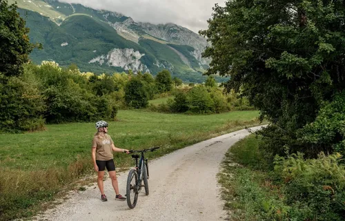Cyclist standing on road with bike admiring view of mountains and countryside, Abruzzo, Italy