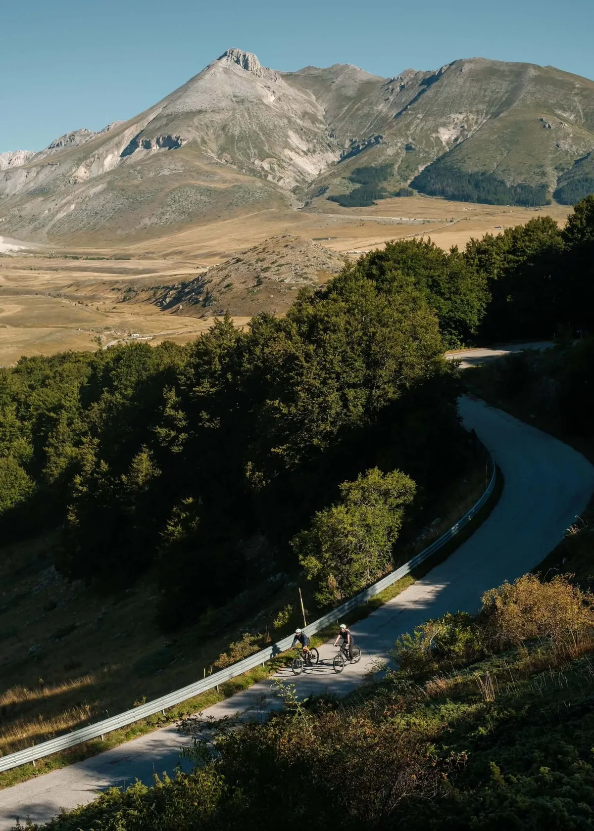 Cyclists on road with mountain backdrop, Campo Imperatore, Abruzzo. Italy