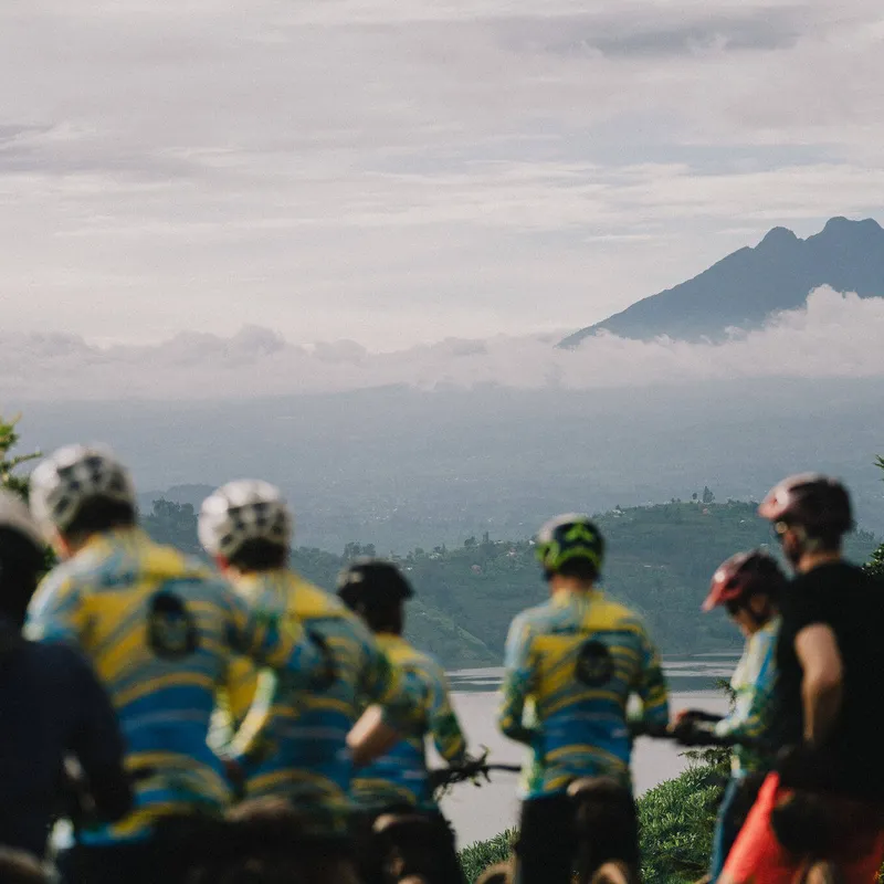 Group of slow cyclists admiring view of volcano, Northern Rwanda