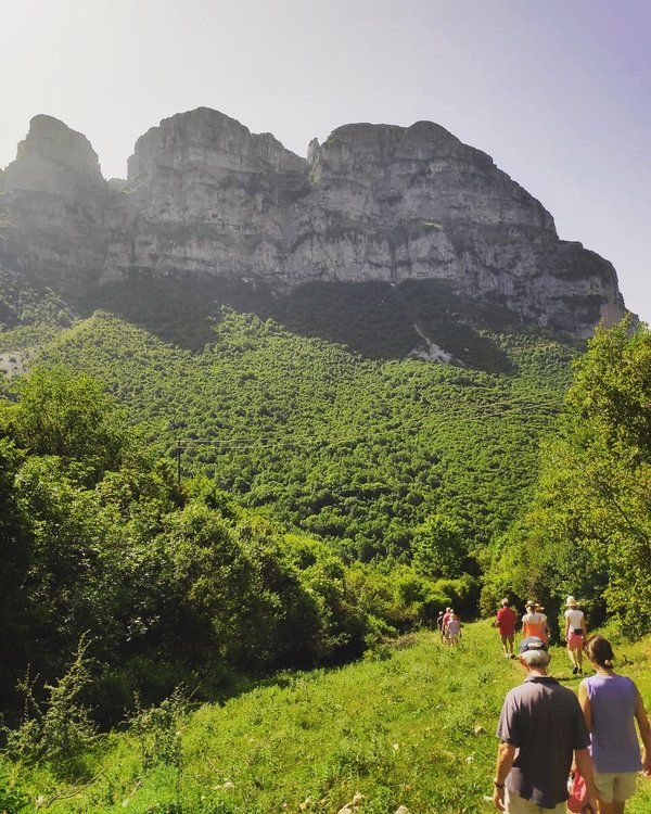 Walkers before green hills and mountains, Zagori, Greece