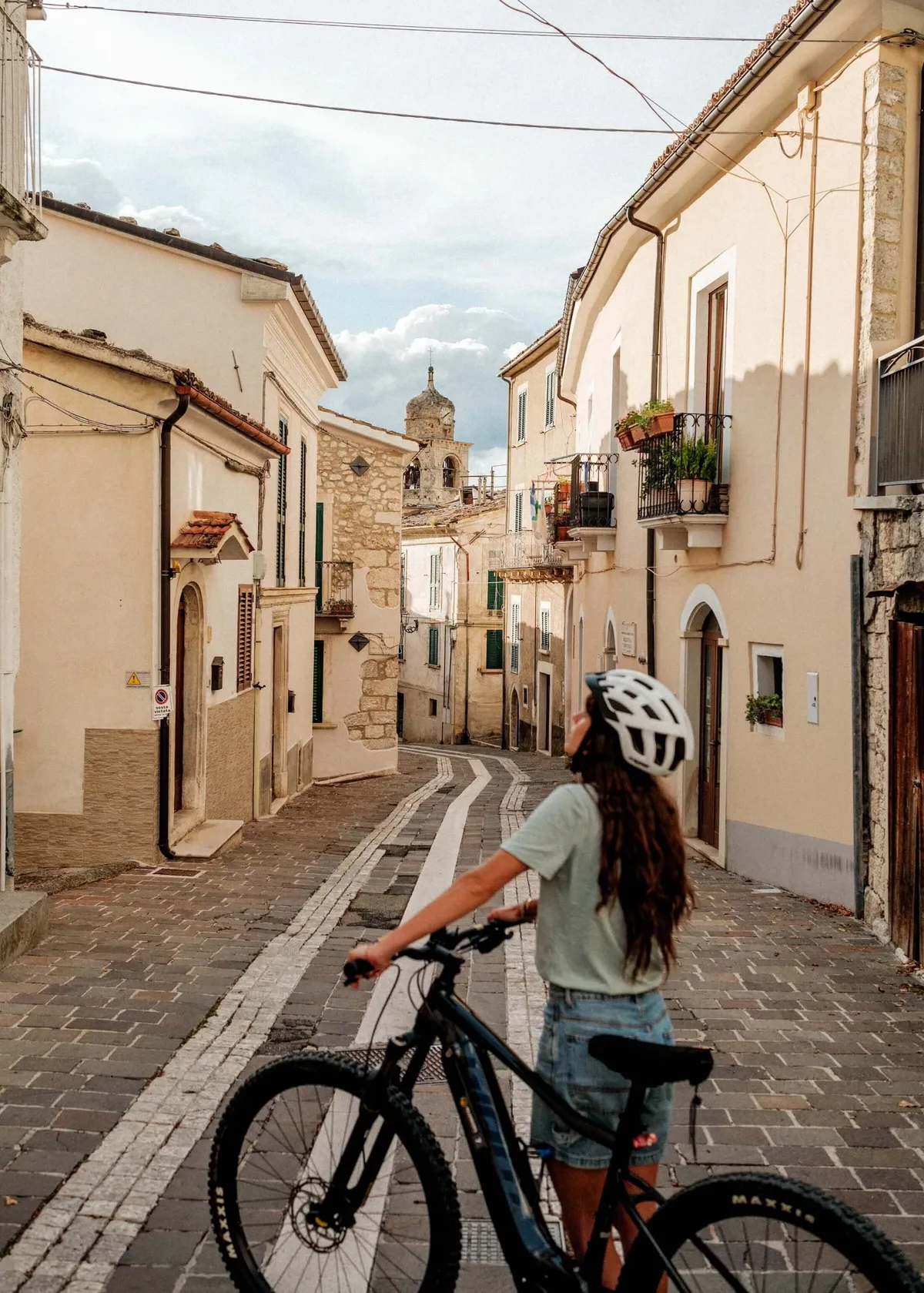 Female cyclist and bike standing in street around Caramanico, Abruzzo, Italy