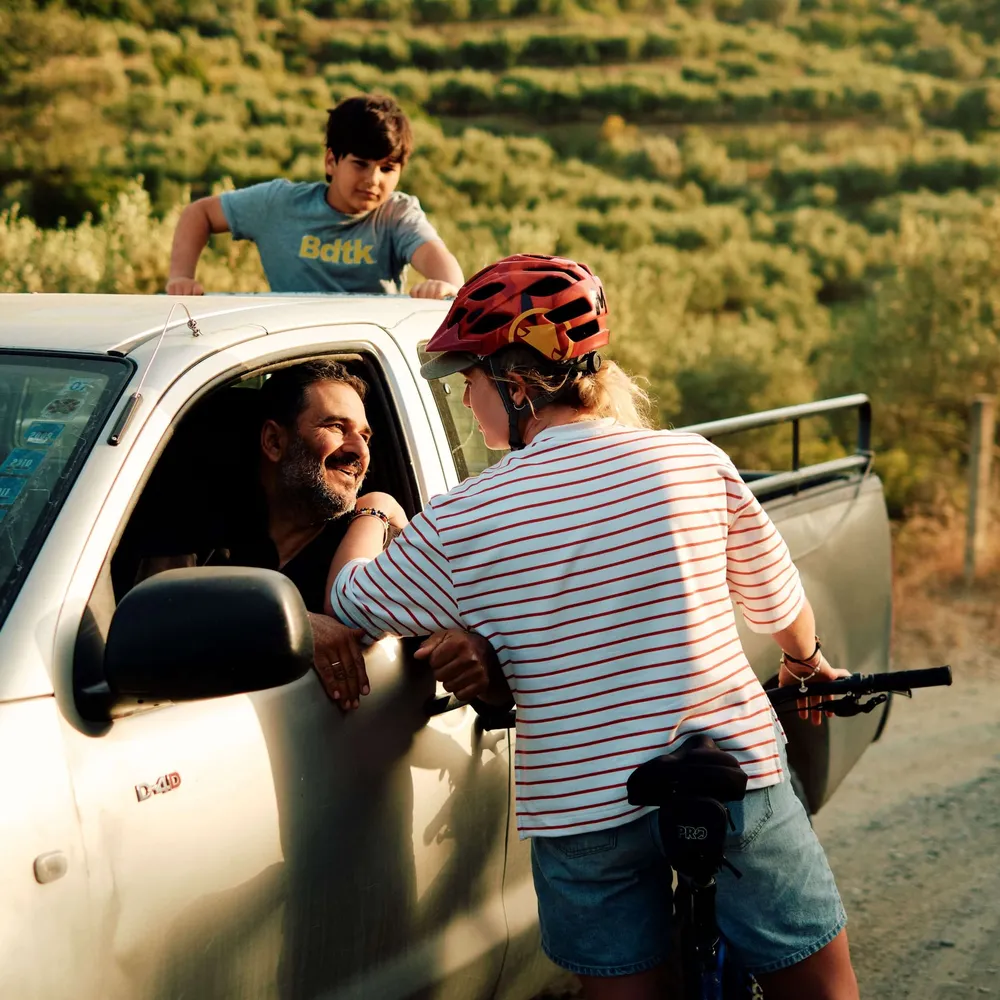 A solo female traveller on her bike chatting to a local in a car in Crete