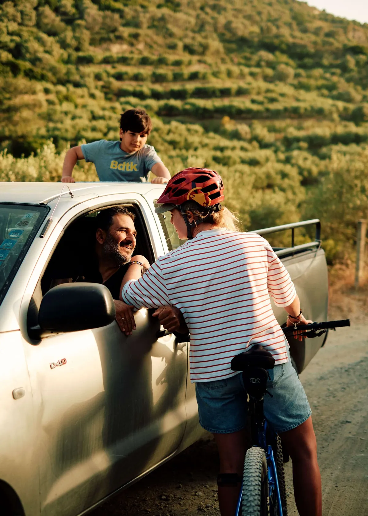 A solo female traveller on her bike chatting to a local in a car in Crete