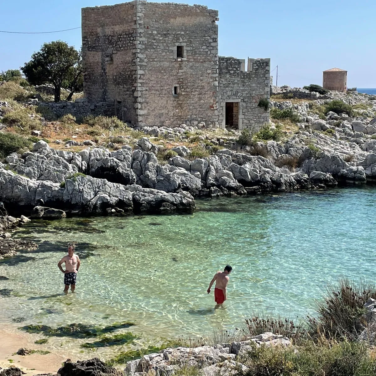 Cyclists relax at the beach in a cove, Mani Peninsula, Greece