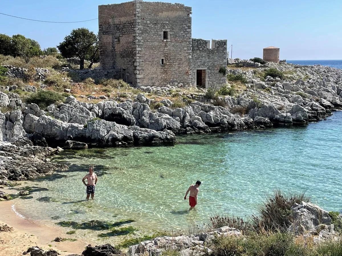 Cyclists relax at the beach in a cove, Mani Peninsula, Greece