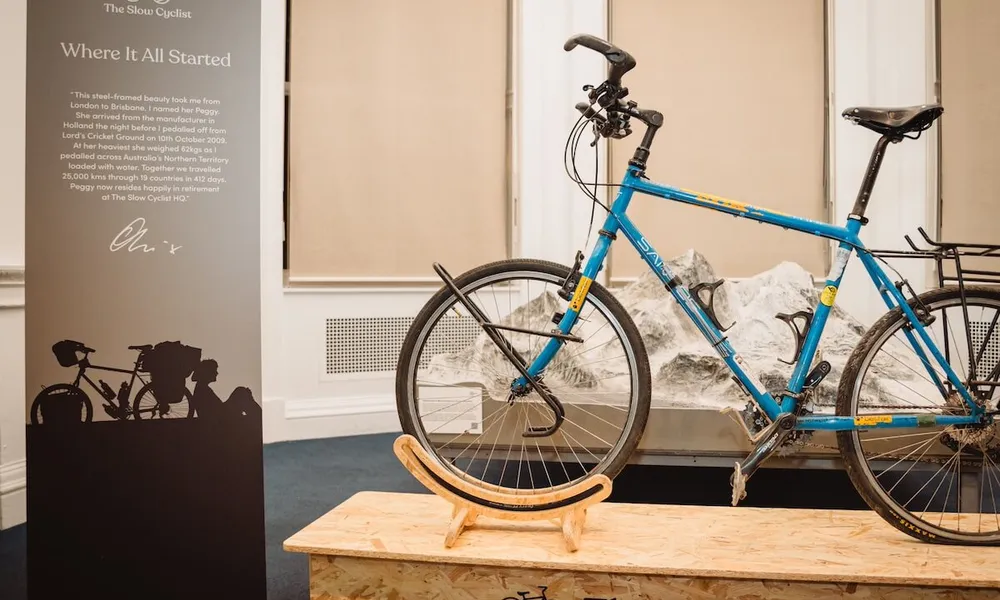 Oli bike on wooden plinth in front of sign - 10 yr party where it all started