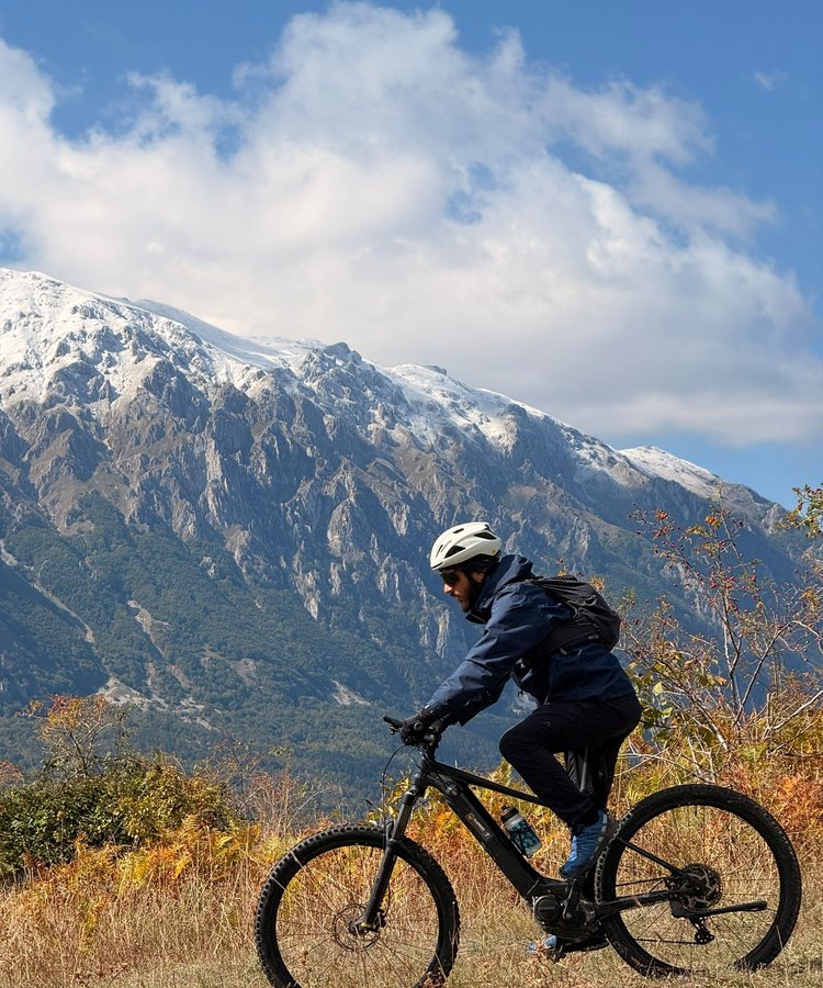 Cyclist on a road in front of snowy mountain top , Abruzzo Italy