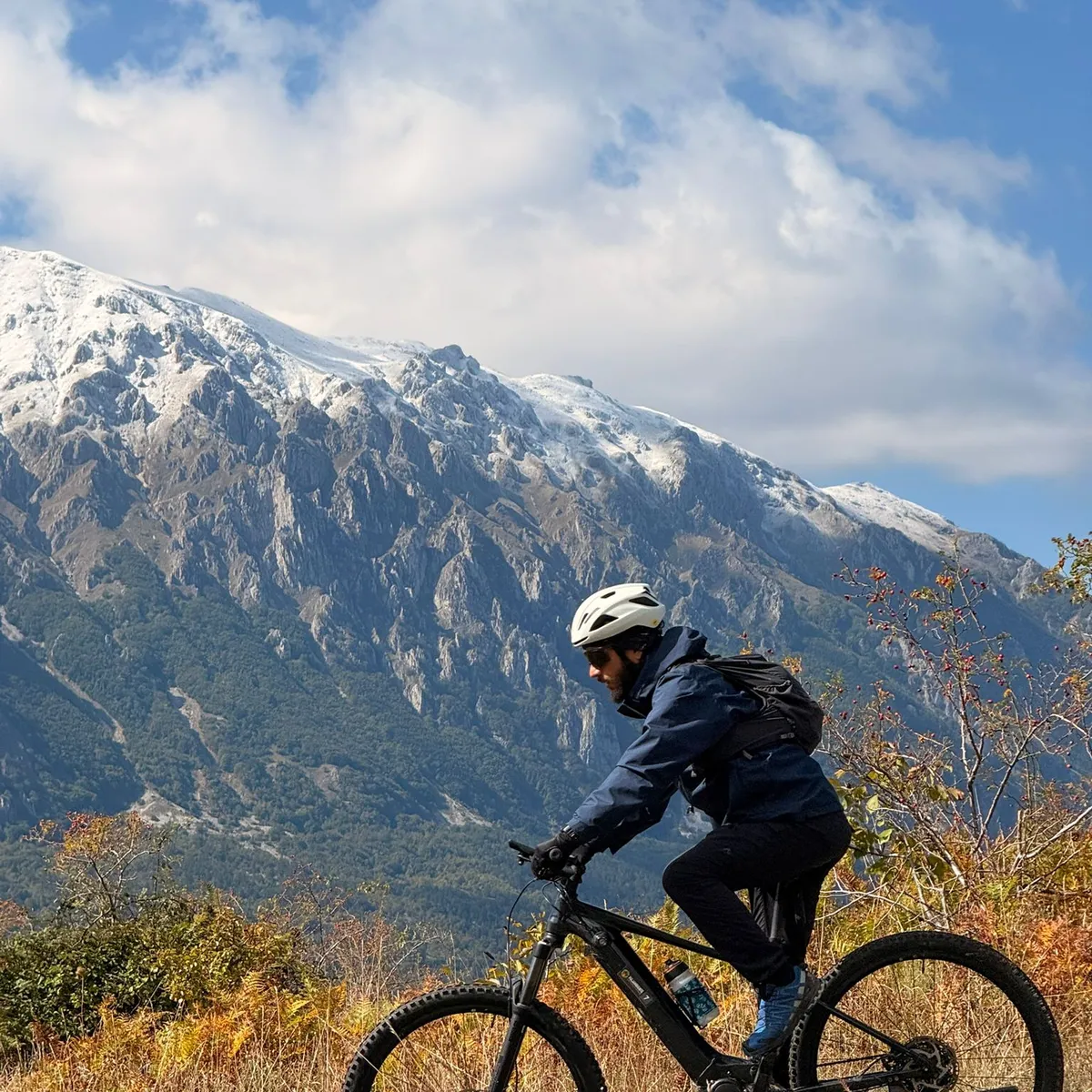 Cyclist on a road in front of snowy mountain top , Abruzzo Italy
