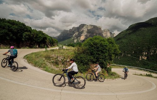 Slow Cyclists Riding Around A Hairpin Bend In Zagori Greece