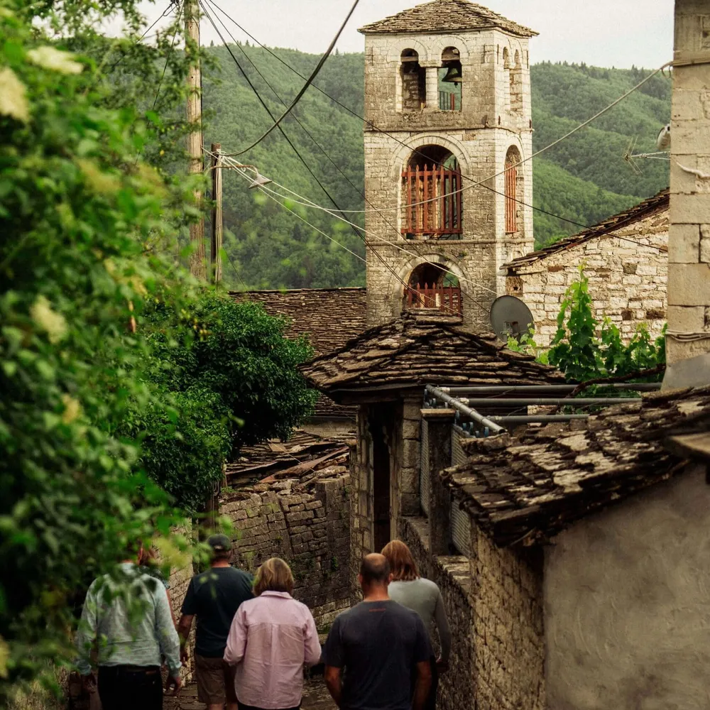 Slow Cyclist walking through the traditional stone village of Dilofo in Zagori, Greece.