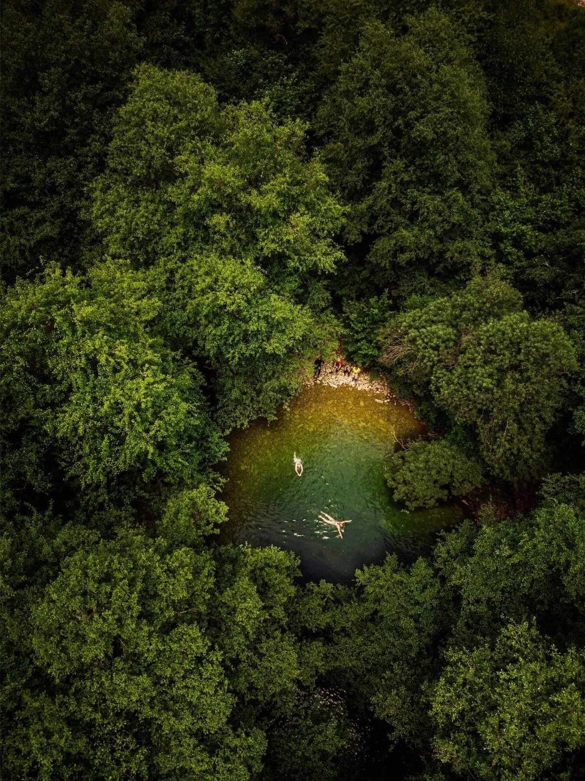 Slow Cyclists swimming in a natural pool among the trees in Zagori, Greece