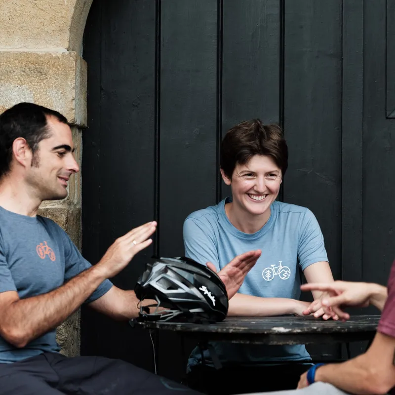 A group of Slow Cyclists and guests sitting at a table in Spanish Basque Country, taking a break from riding