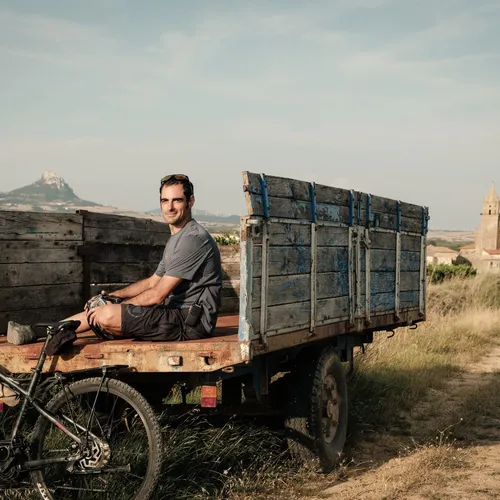 Slow Cyclist guide Felipe sitting on the back of a cart with a Spanish Basque village in the background