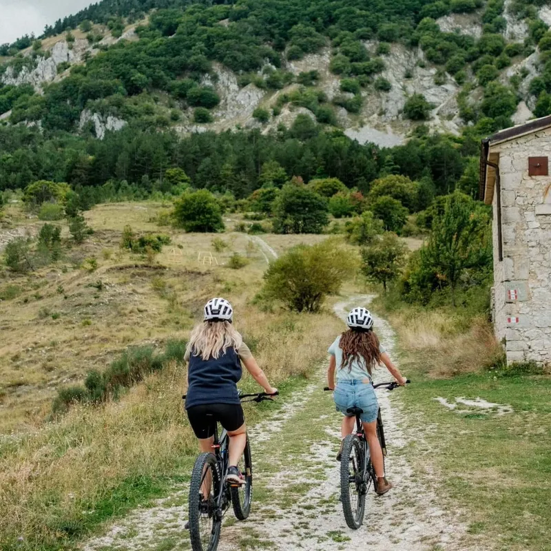 Two women cycle up a track, Roccaramanico, Abruzzo, Italy