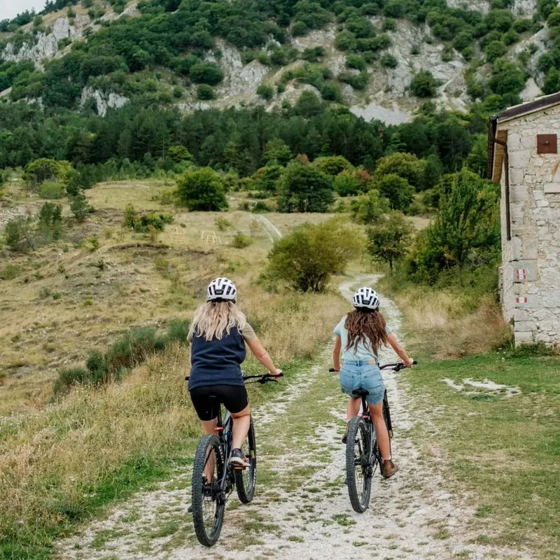 Two women cycle up a track, Roccaramanico, Abruzzo, Italy