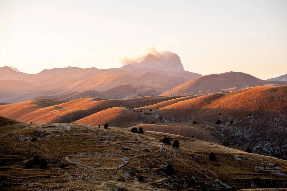 View of stone foundations across hills and field, Castel of Rocca Calascio Hike, Abruzzo, Italy