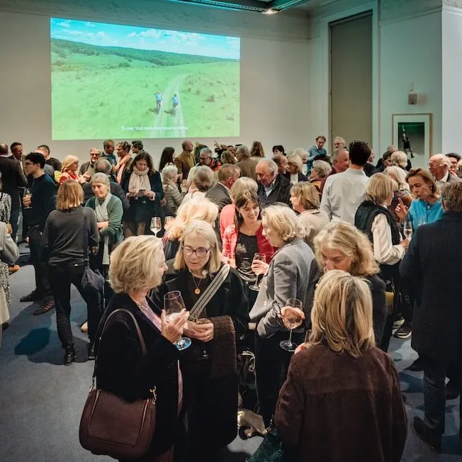 crowds of guests at 10 year anniversary party with brand film in background